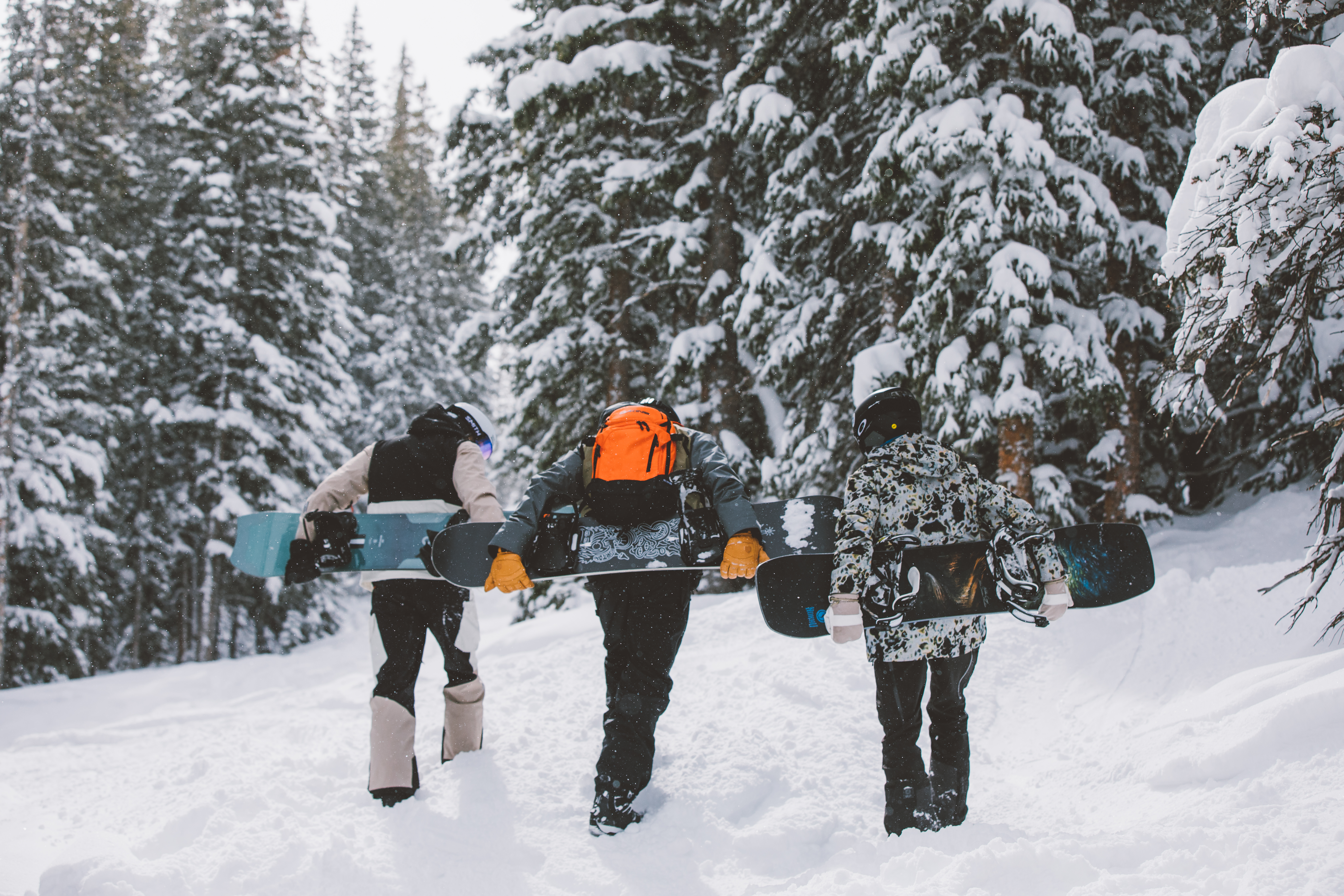 Three men carrying snowboards from Sun & Ski Sports